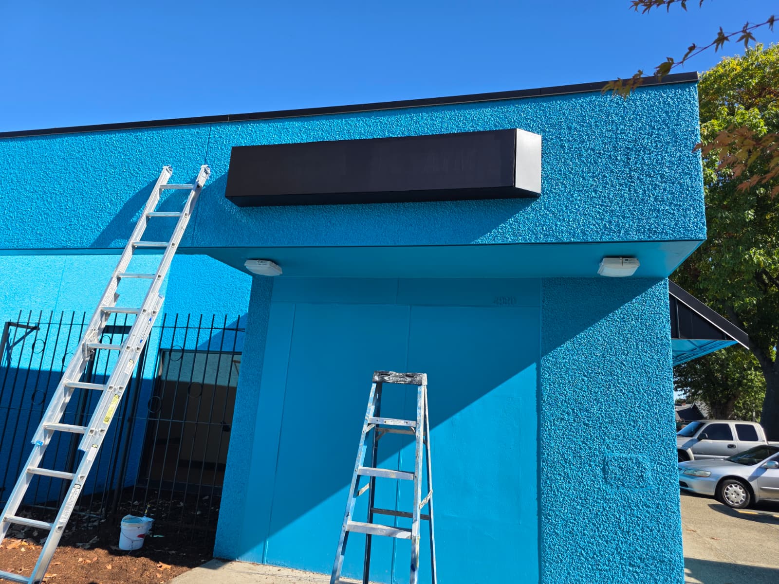 Commercial storefront exterior repainted in a bold turquoise blue with black accents