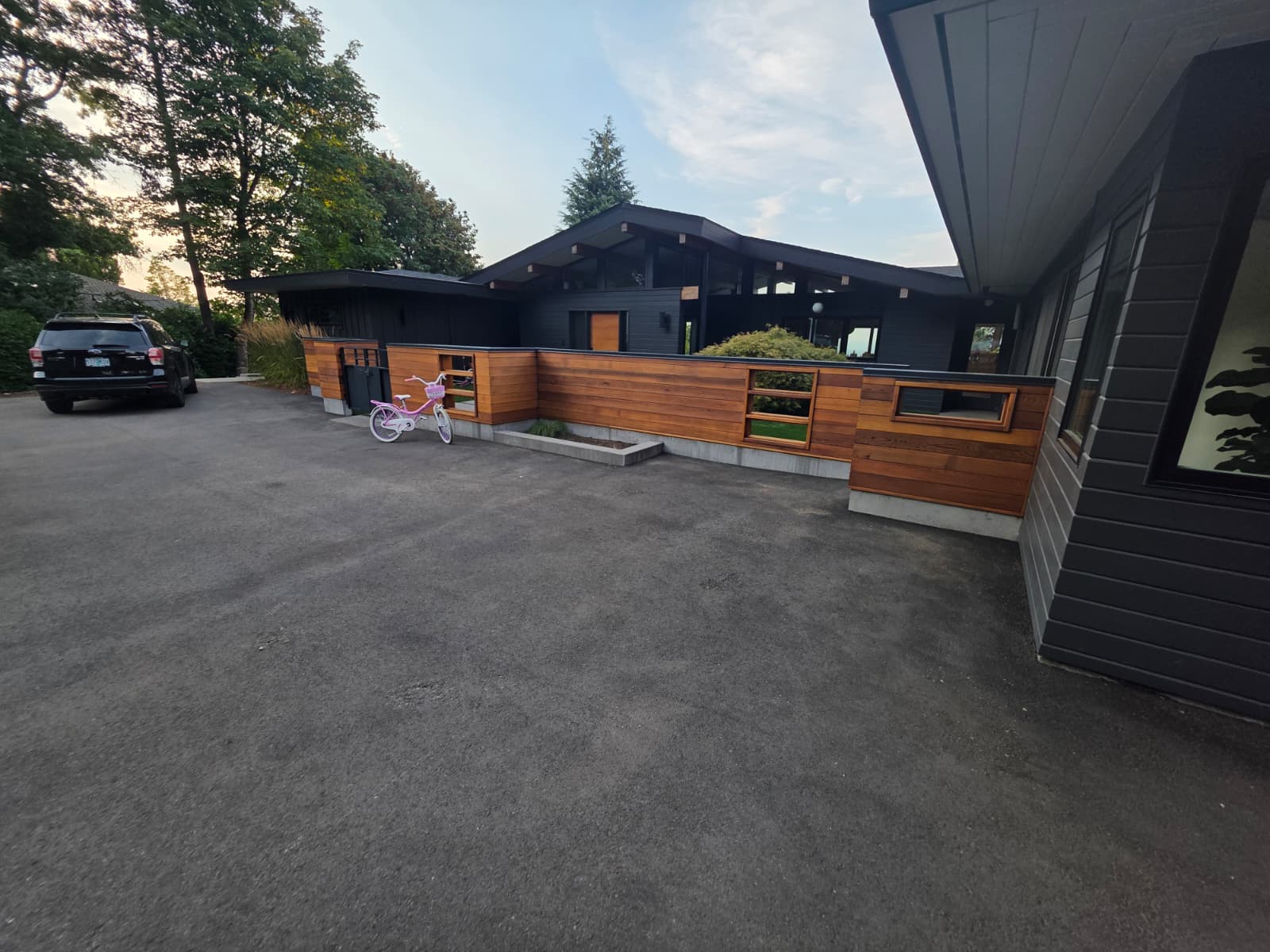 Contemporary single-story home exterior finished in matte black with warm natural cedar wood siding accents