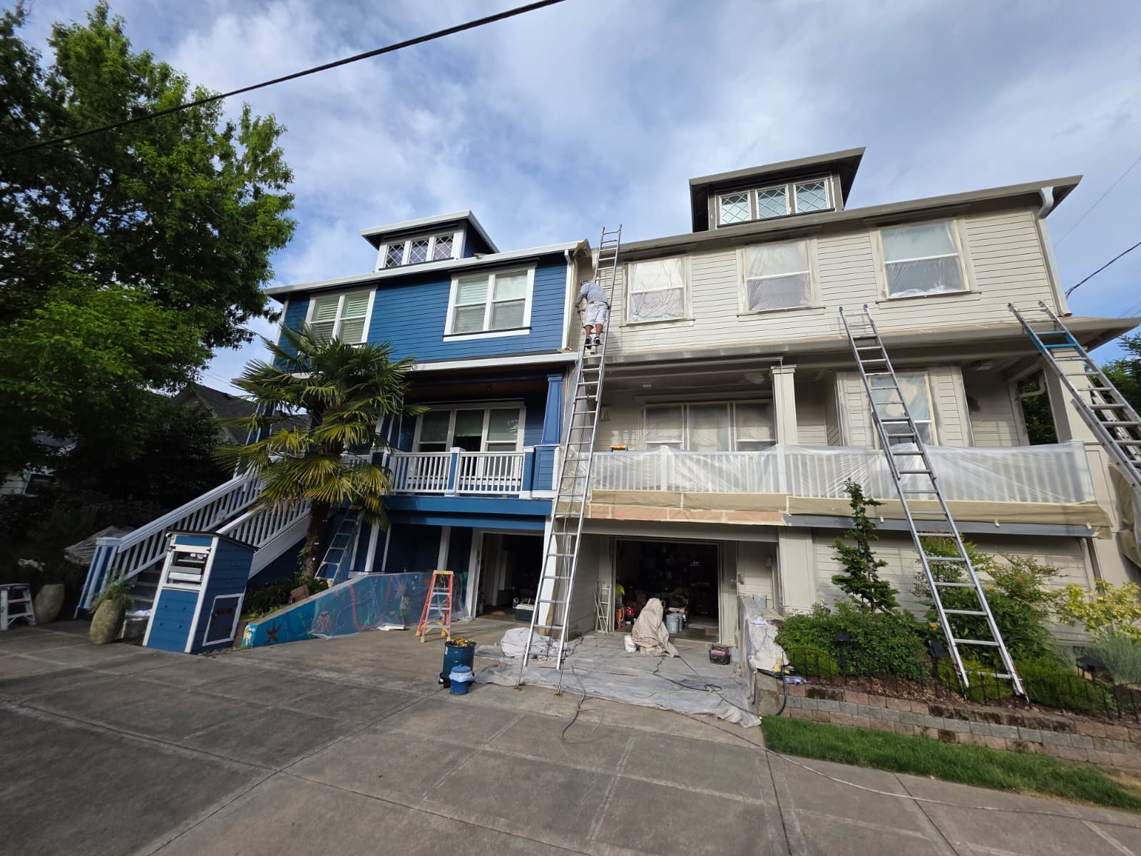 Multi-story home mid-project with prepped siding and crew on ladders