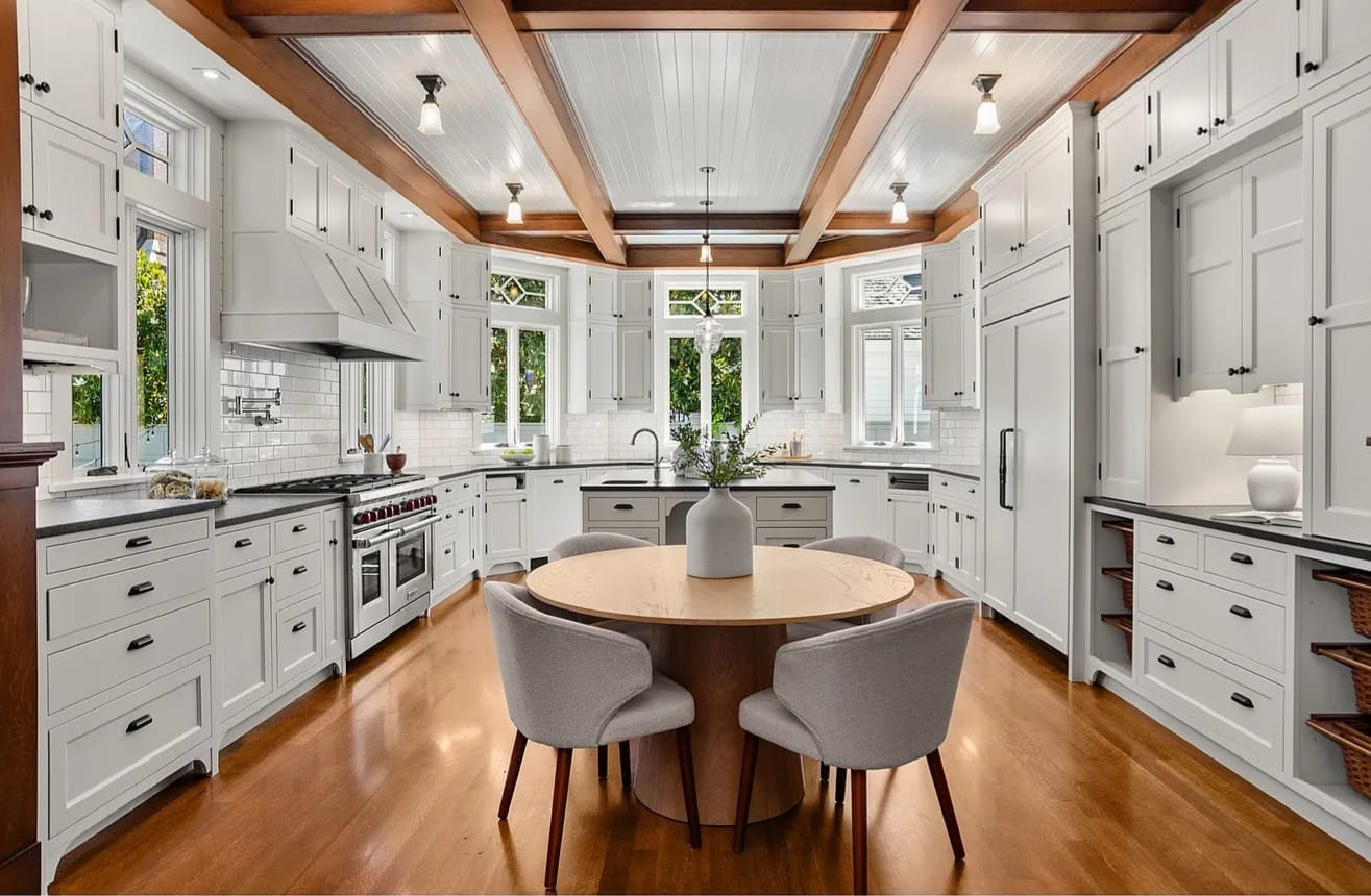Bright kitchen with refinished white cabinetry, exposed wood beams, and dark countertops