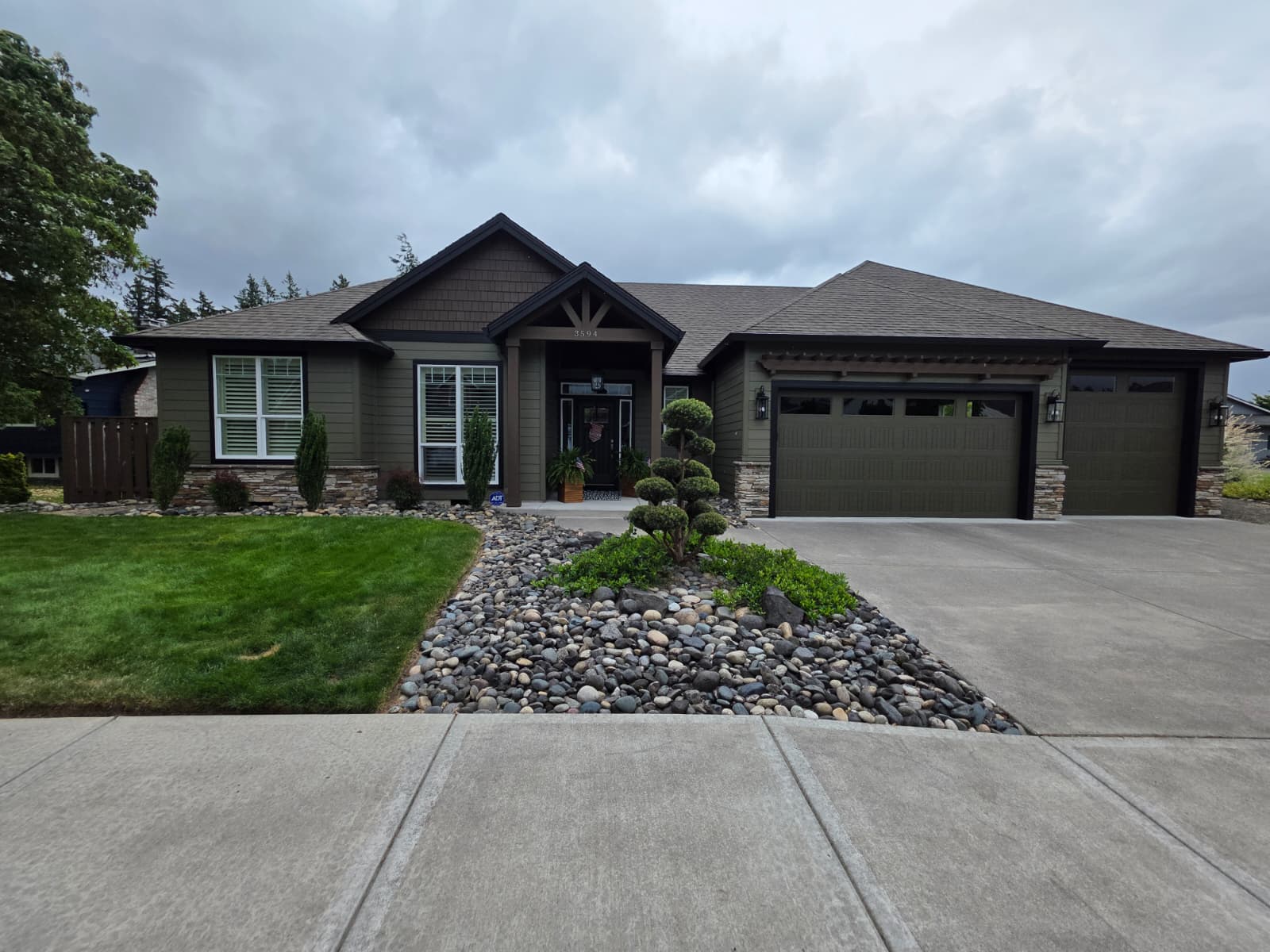 Completed exterior of an upscale single-story home painted in a rich olive and charcoal palette